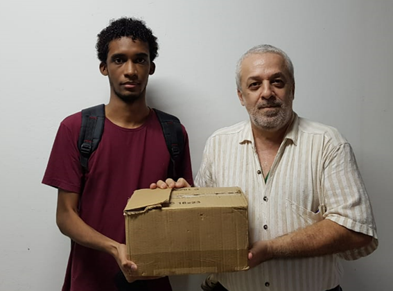 Imagem 1 – Higor e Ricardo com os livros doados em uma caixa